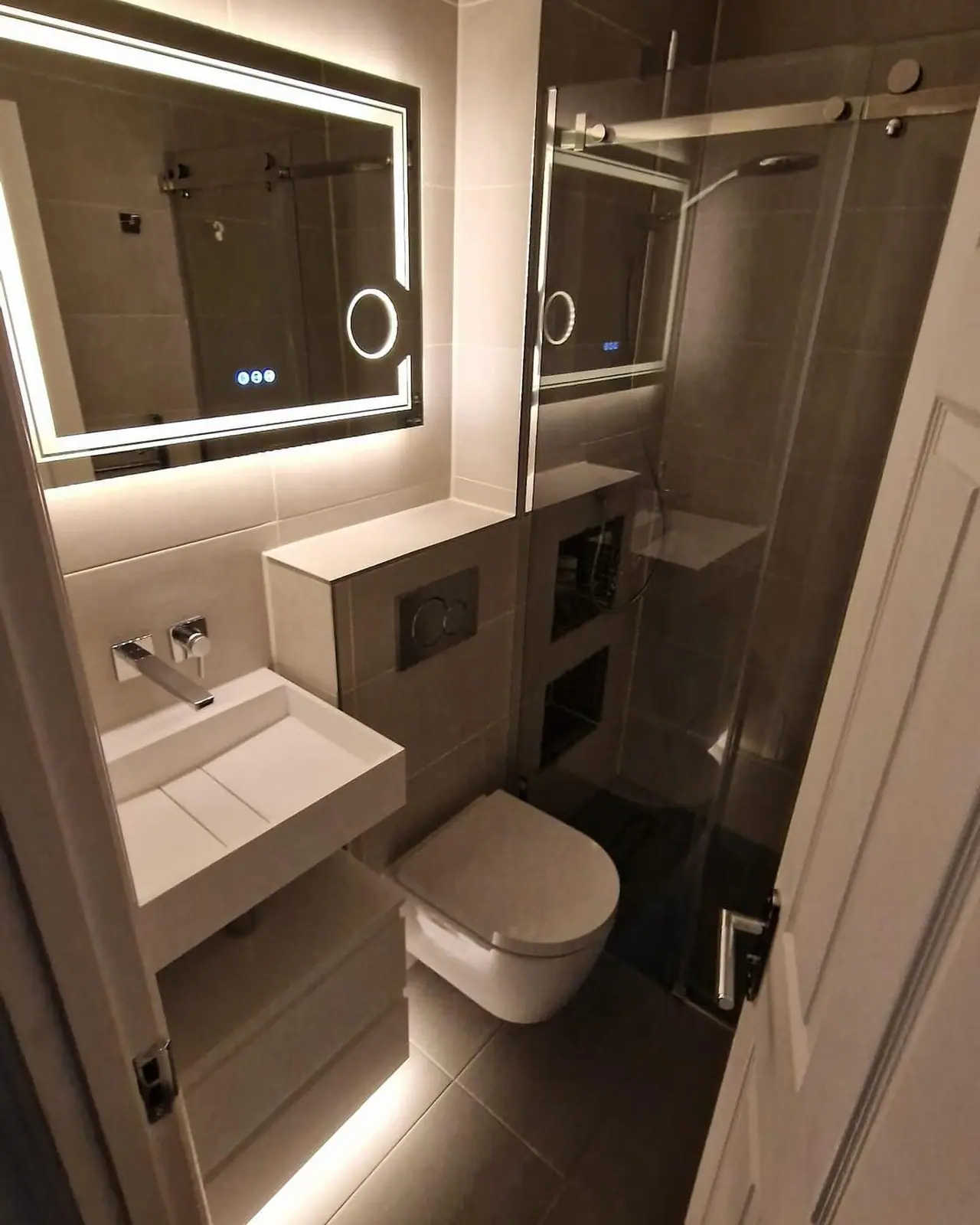 The finished en suite with lit mirror, wall-hung basin and toilet