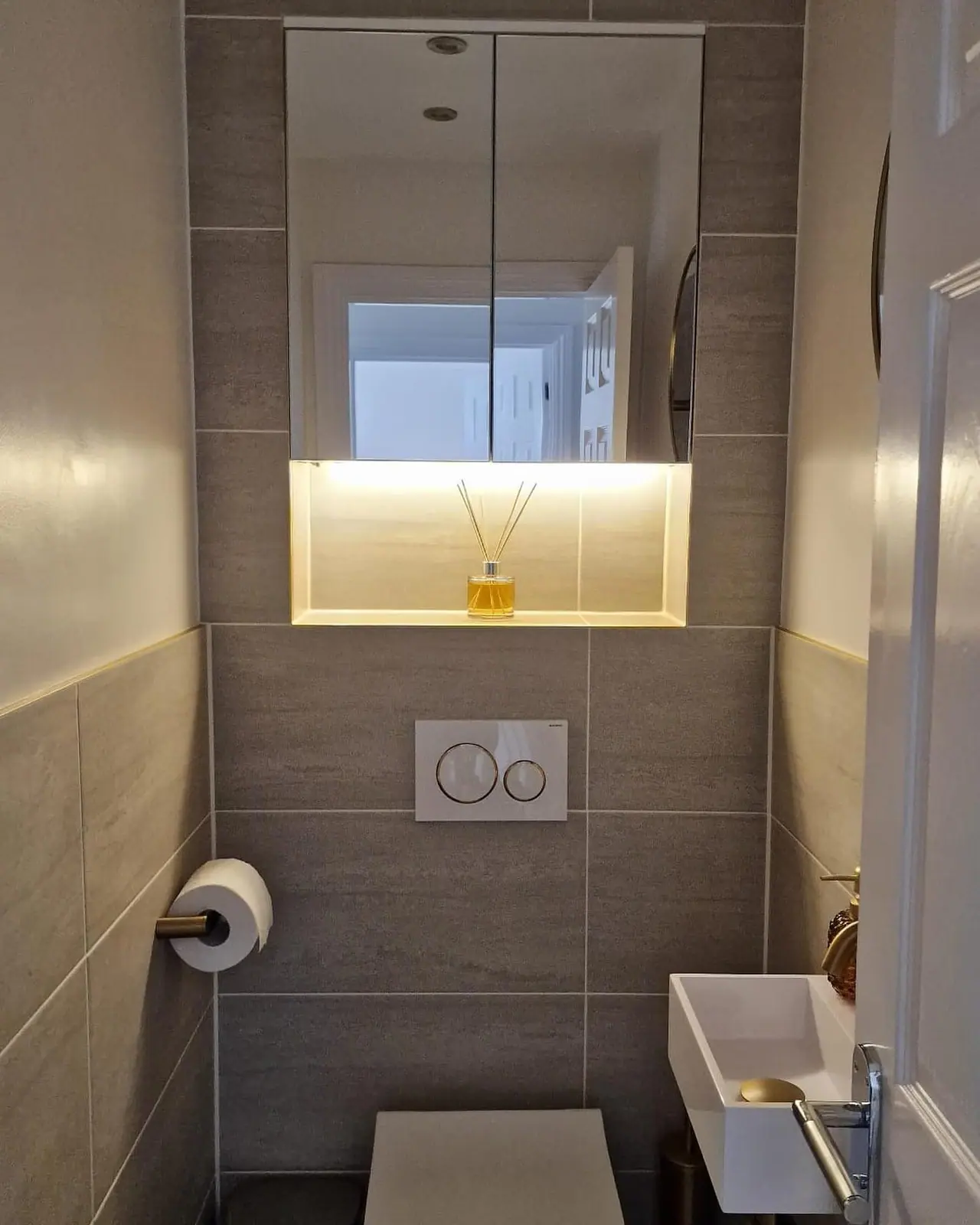 The cloakroom WC in the same house, with a lit recessed shelf and mirror cabinet