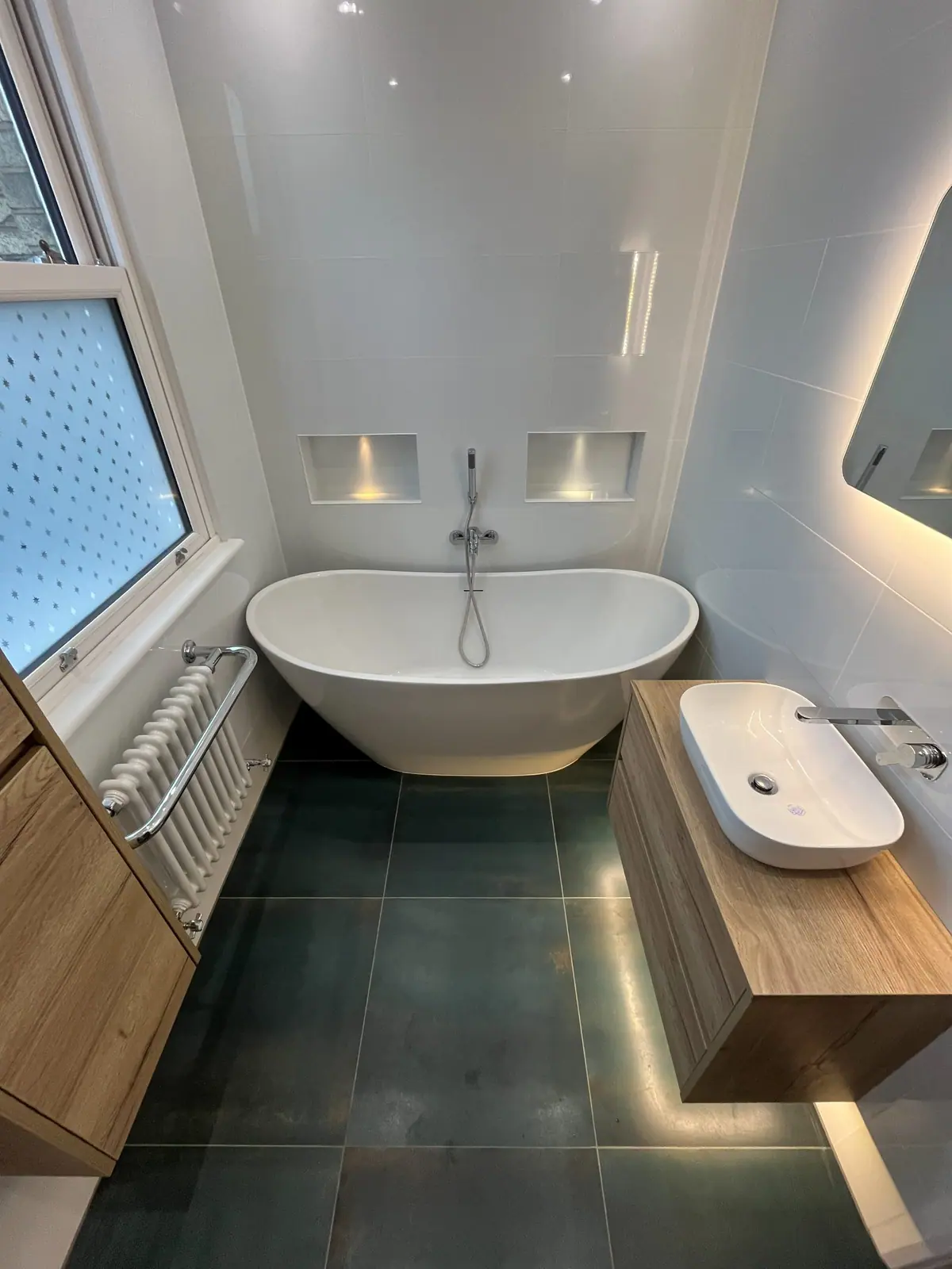 The finished bathroom with the freestanding bath between two lit niches