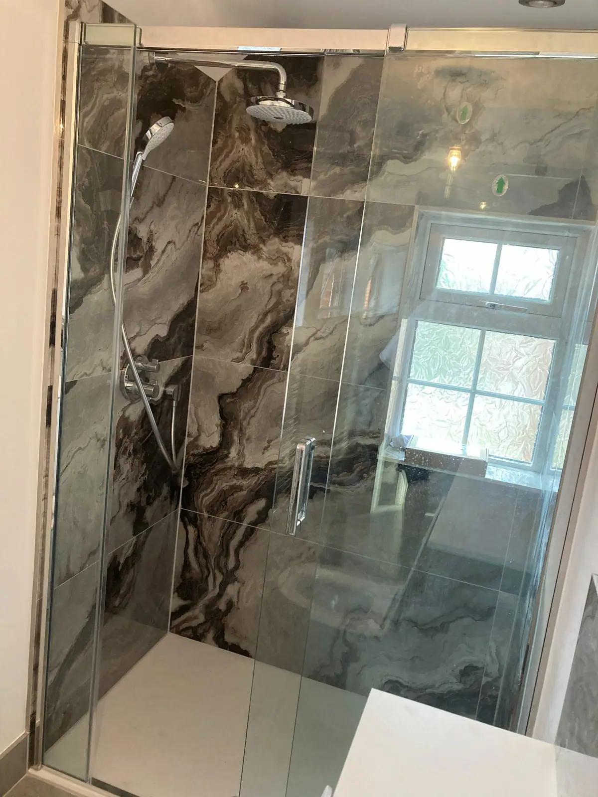 The walk-in shower with marble-effect panels and a rainfall head