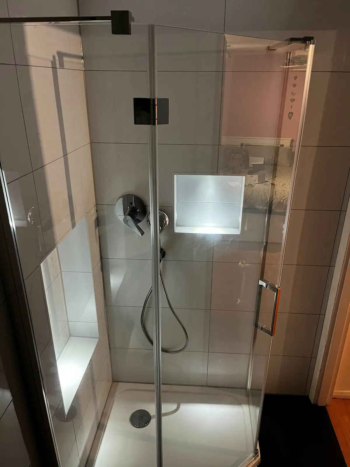 The new shower with frameless glass, large-format white tiles and a lit niche