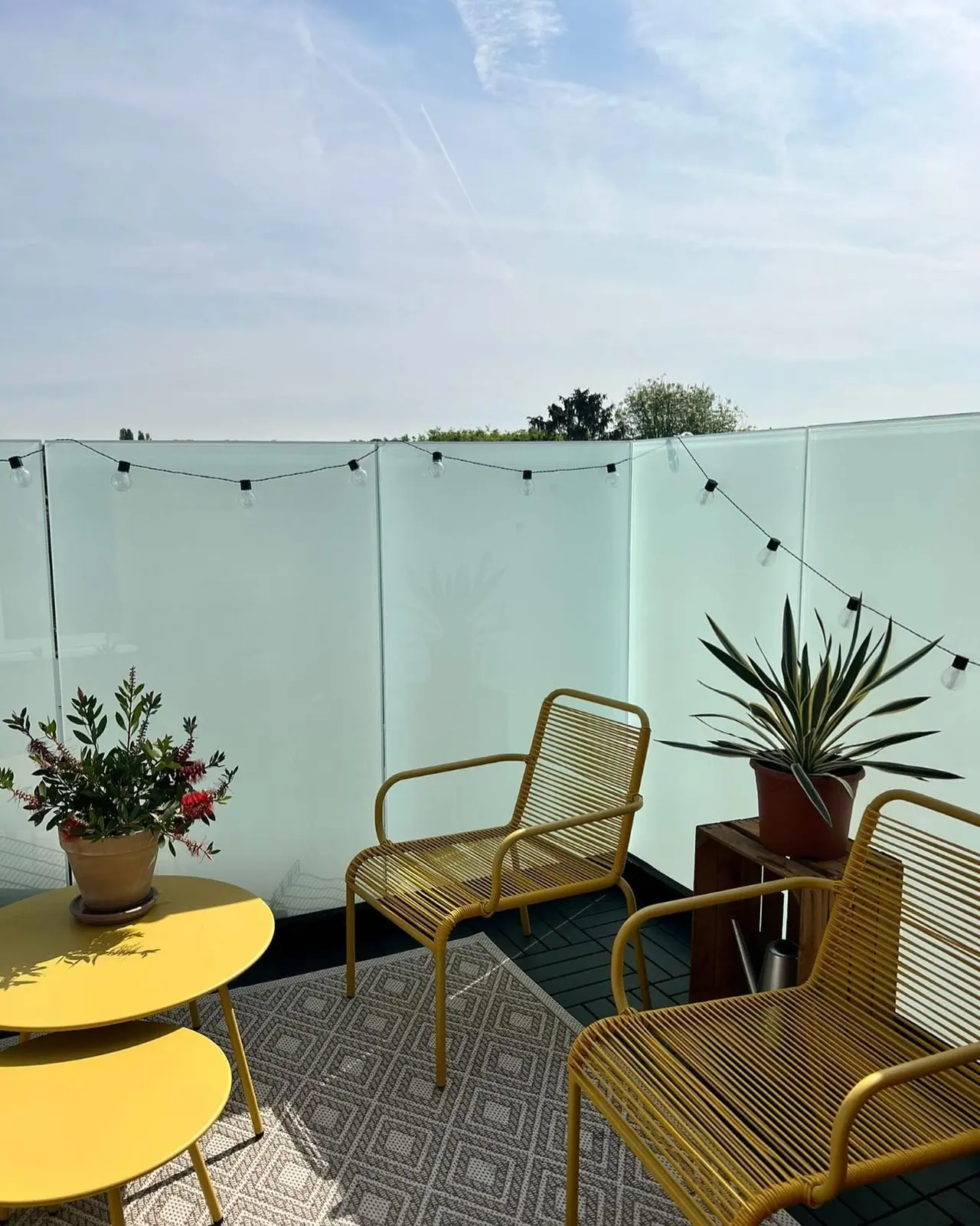 The finished roof terrace with a frosted glass balustrade, furniture and festoon lights