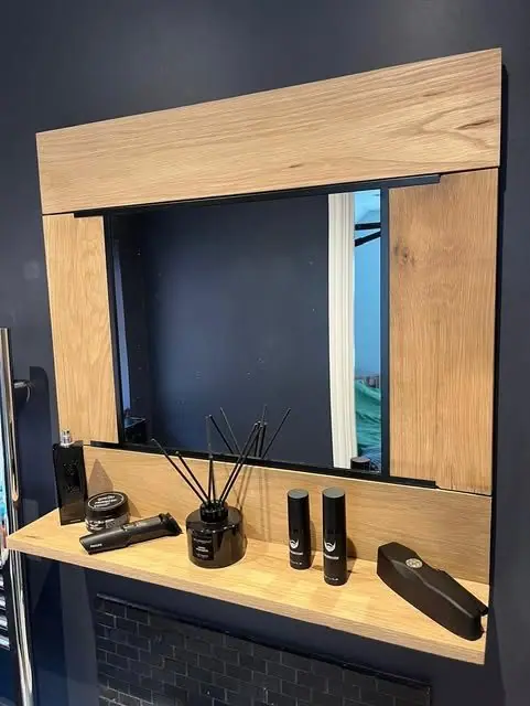 An oak-framed mirror with a shelf built into the bottom rail