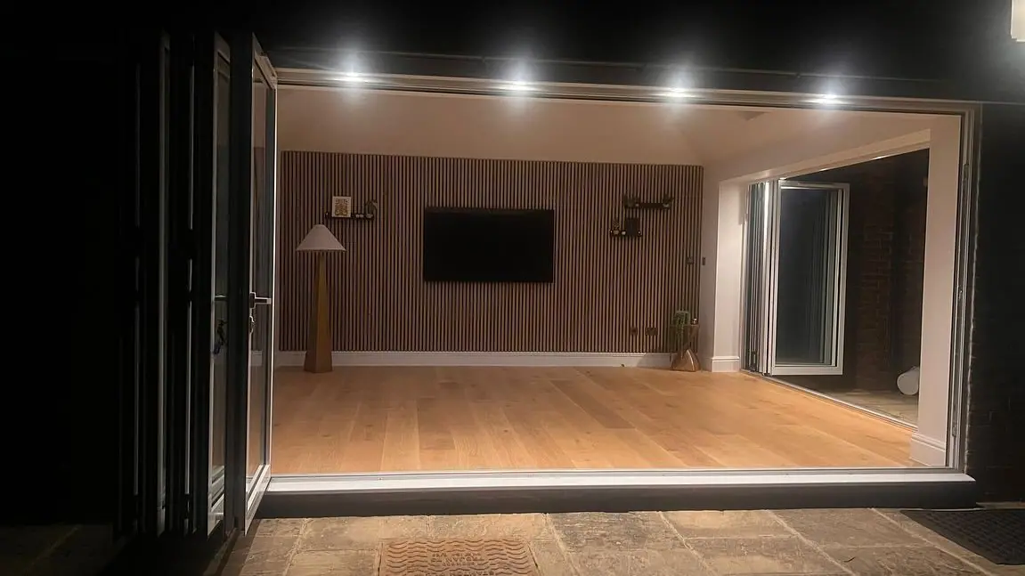 The finished room at night, seen through the open bi-fold doors