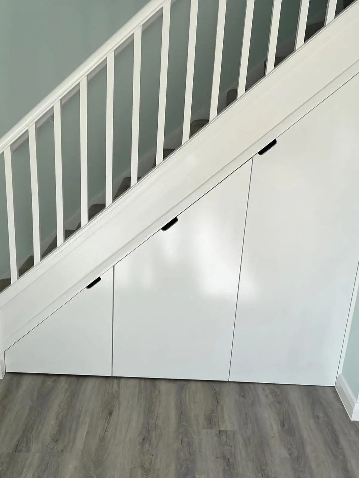 Fitted white doors built into the space under a staircase