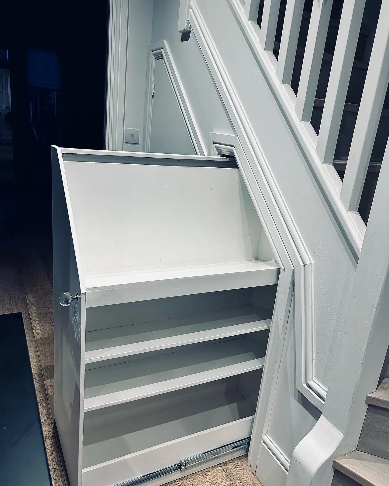 A full-depth pull-out shelving unit drawn out from under the stairs