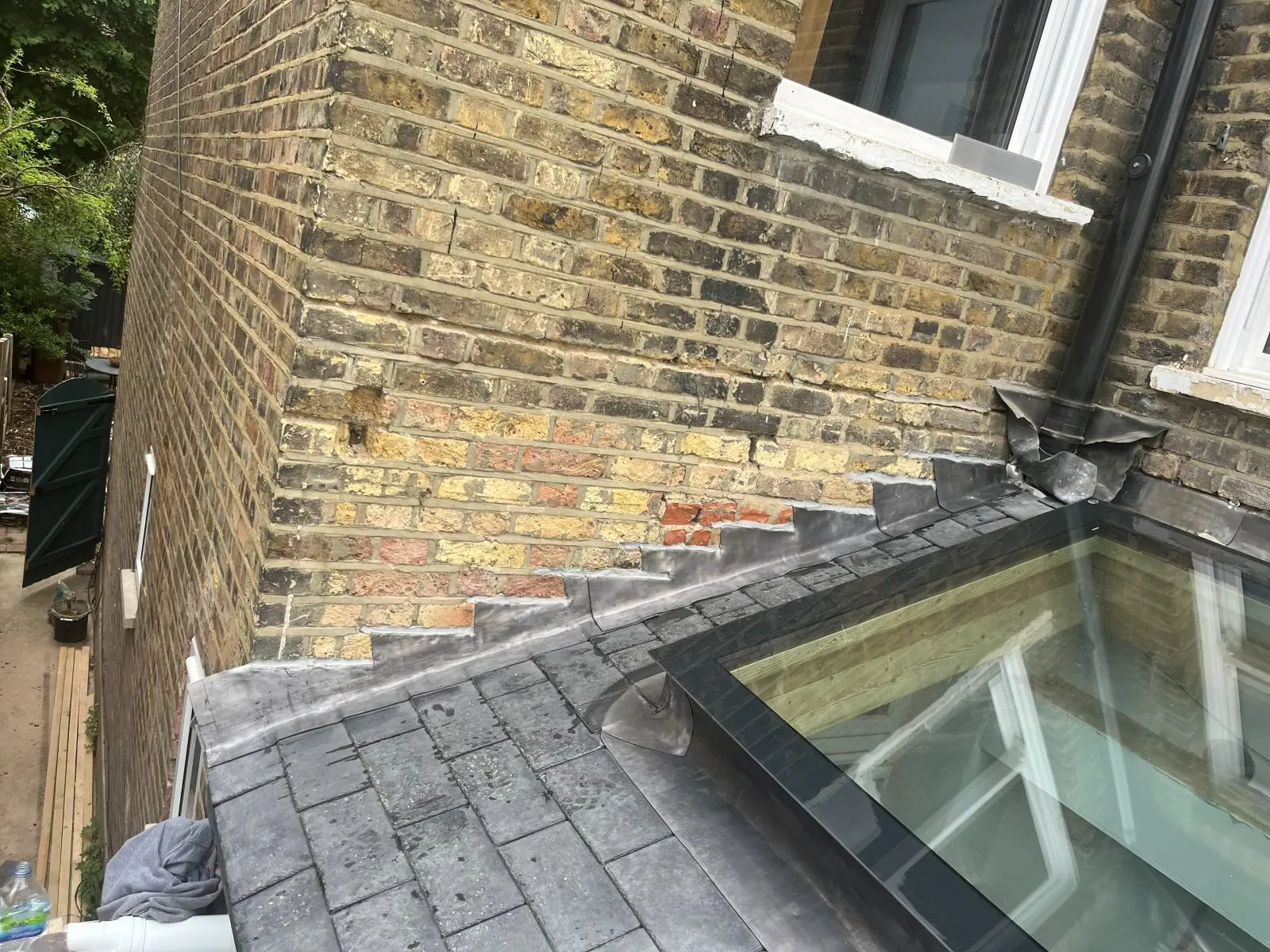 Stepped lead flashing on stock brickwork above a slate roof, with the roof light kerb lead-lined