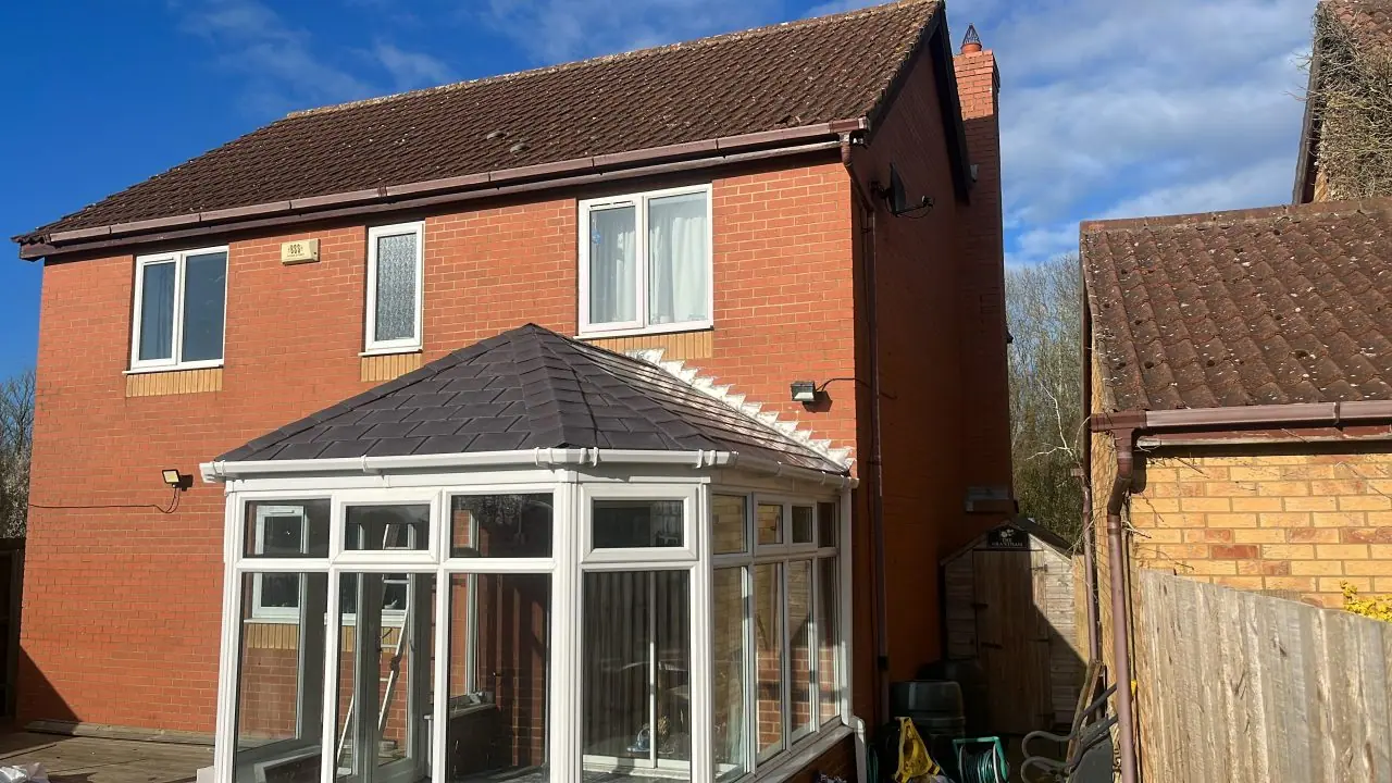 Conservatory finished with a solid anthracite tiled roof against a clear sky