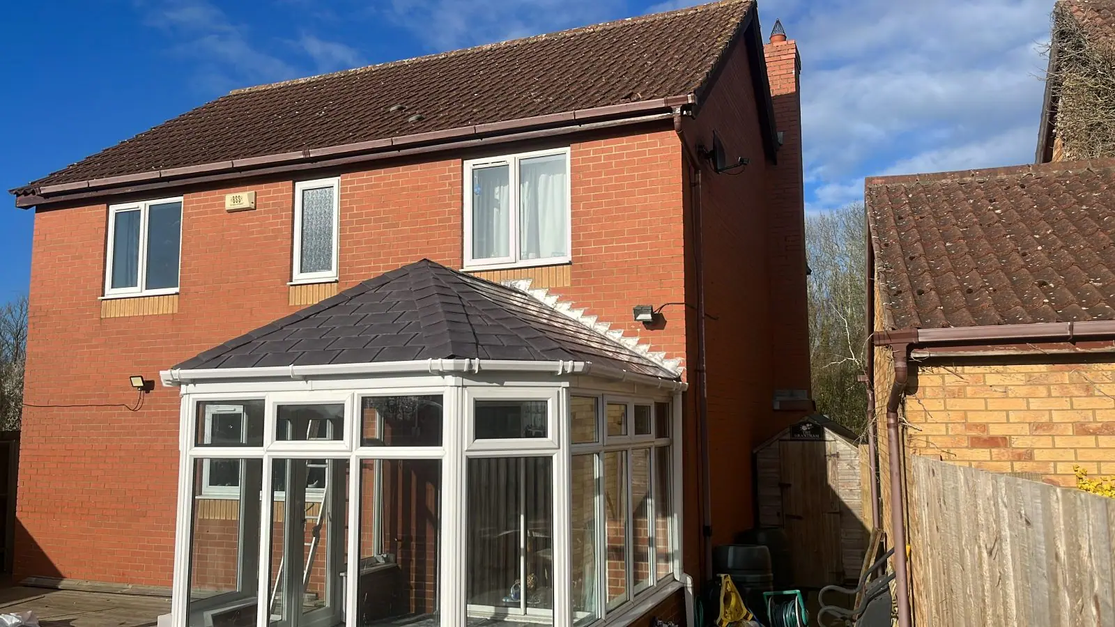 Conservatory finished with a solid anthracite tiled roof against a clear sky