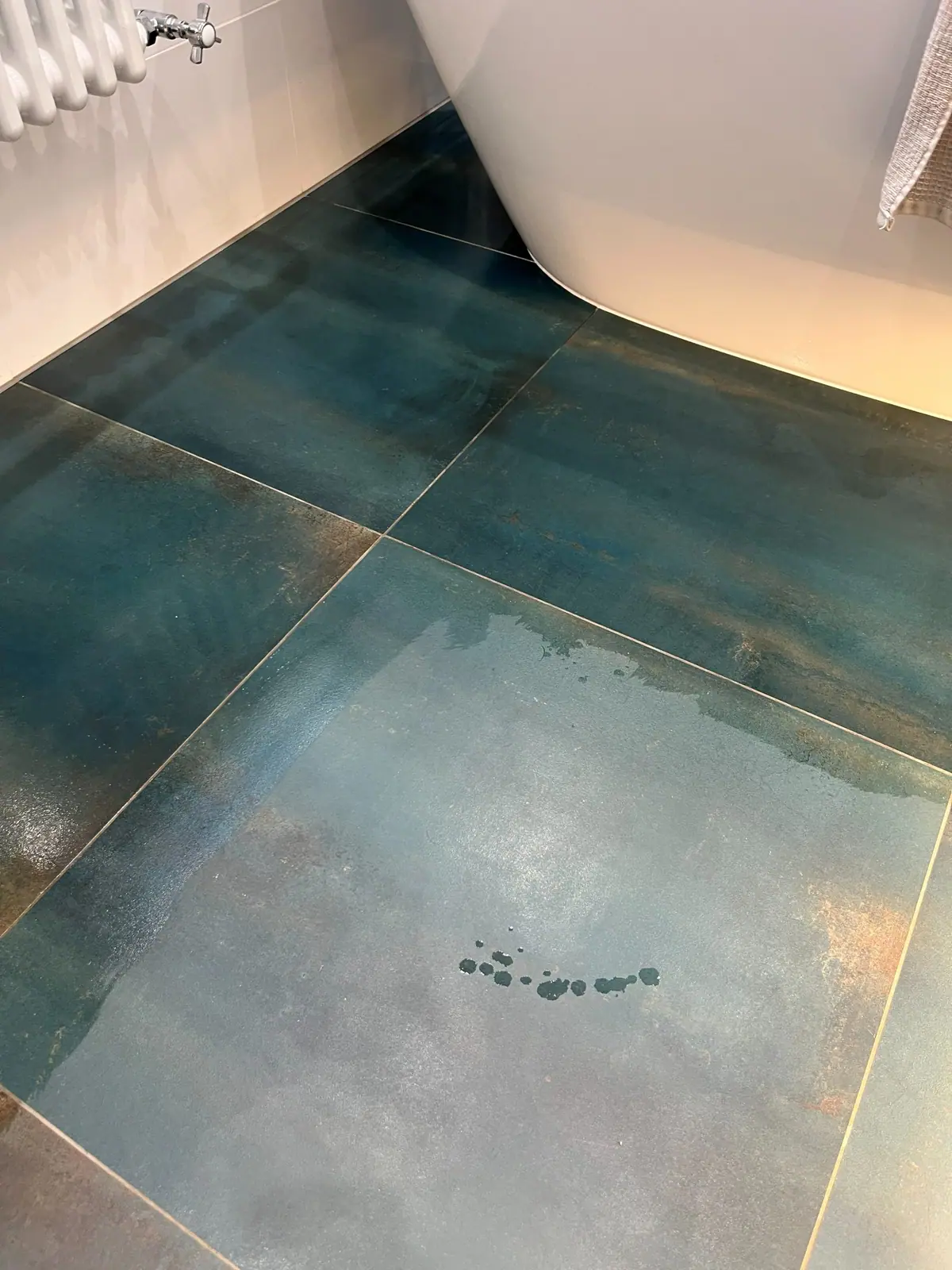 Close view of the teal and copper tiles running up to the freestanding bath, with fine, even grout lines