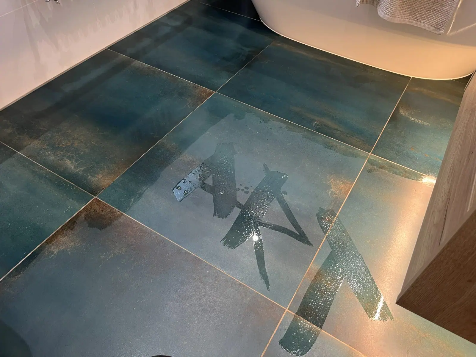 The tiled floor between the bath and the vanity unit, with ART written in water across the tiles