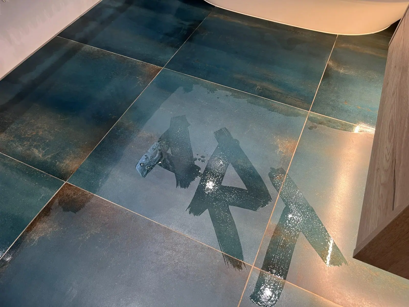 ART written in water across the finished teal floor tiles