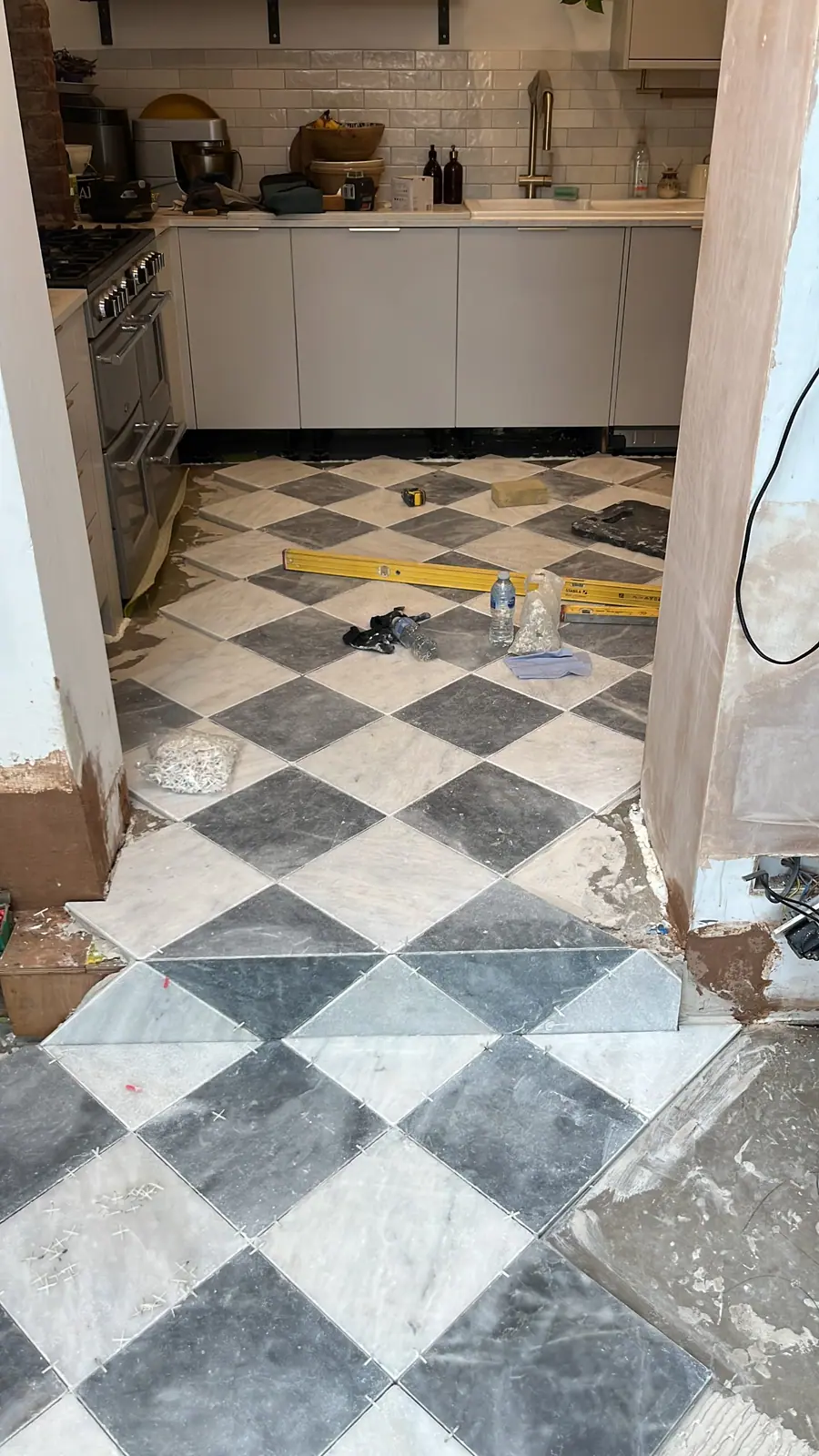 Black and white stone tiles being laid on the diagonal in a chequerboard pattern