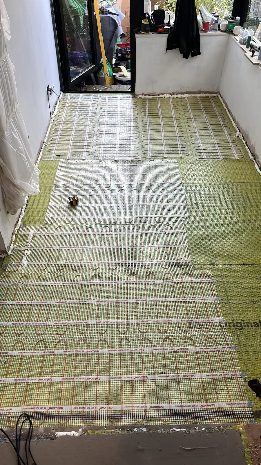 Electric underfloor heating mats laid across the whole floor before the screed
