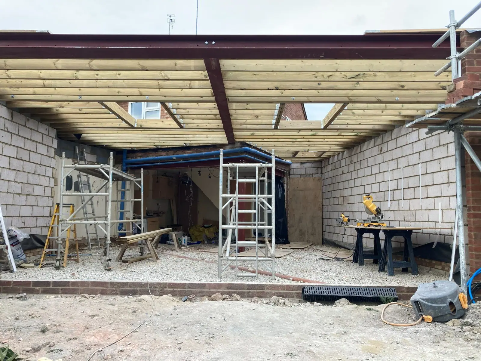 The timber joists of a new extension flat roof spanning between steels, with openings trimmed for roof lights
