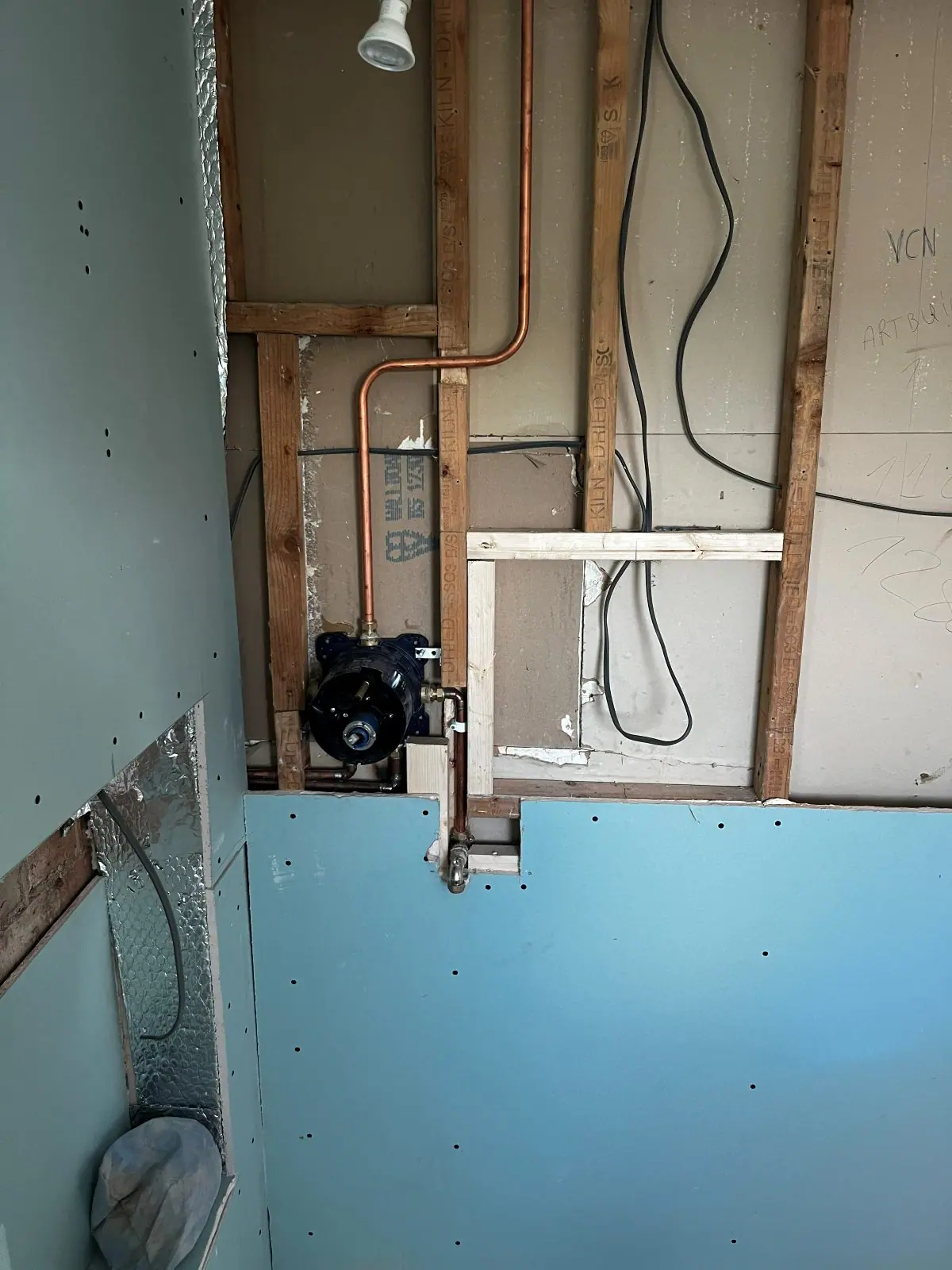 A bathroom stripped to the studwork, with new copper pipework run in and moisture-resistant board fixed to the lower wall