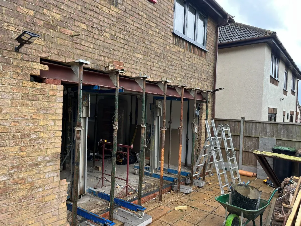 The rear wall of a house held on temporary props while new steel beams go in above the opening