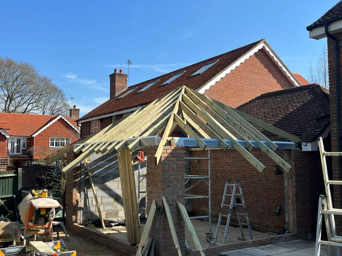 New roof timbers being cut and fixed over the walls of a single storey extension