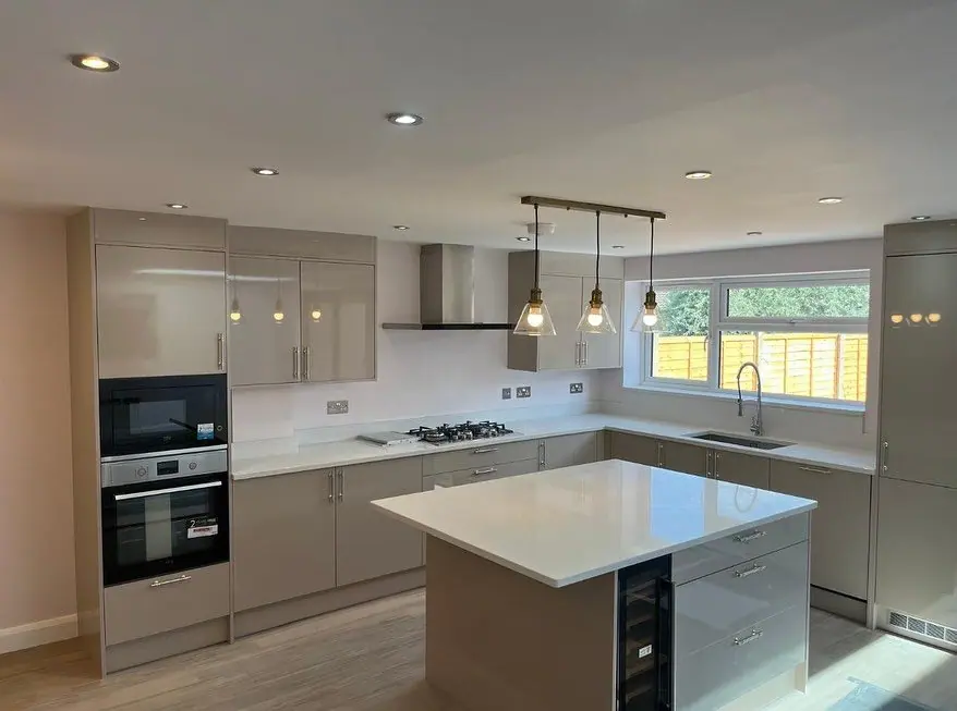 The finished kitchen with an island, pendant lights, built-in ovens and a gas hob