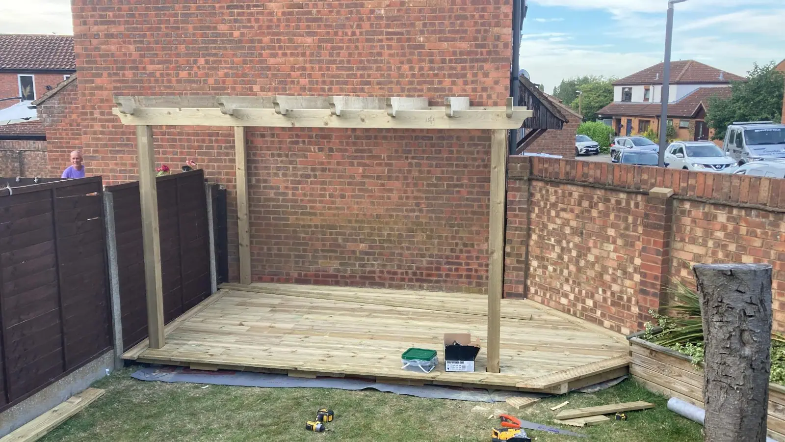 A new timber deck with a pergola over it in the corner of a walled garden