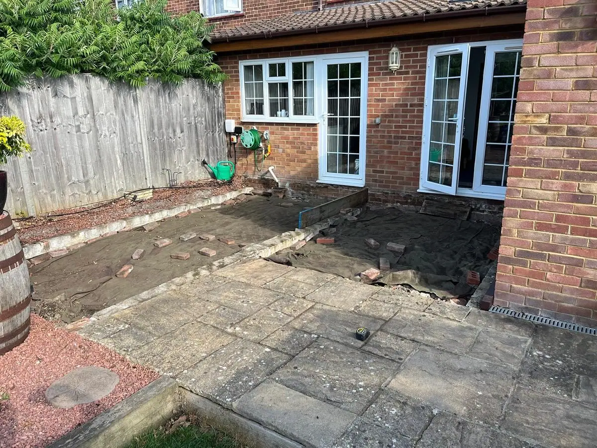 A rear patio of broken slabs and bare earth outside the back doors
