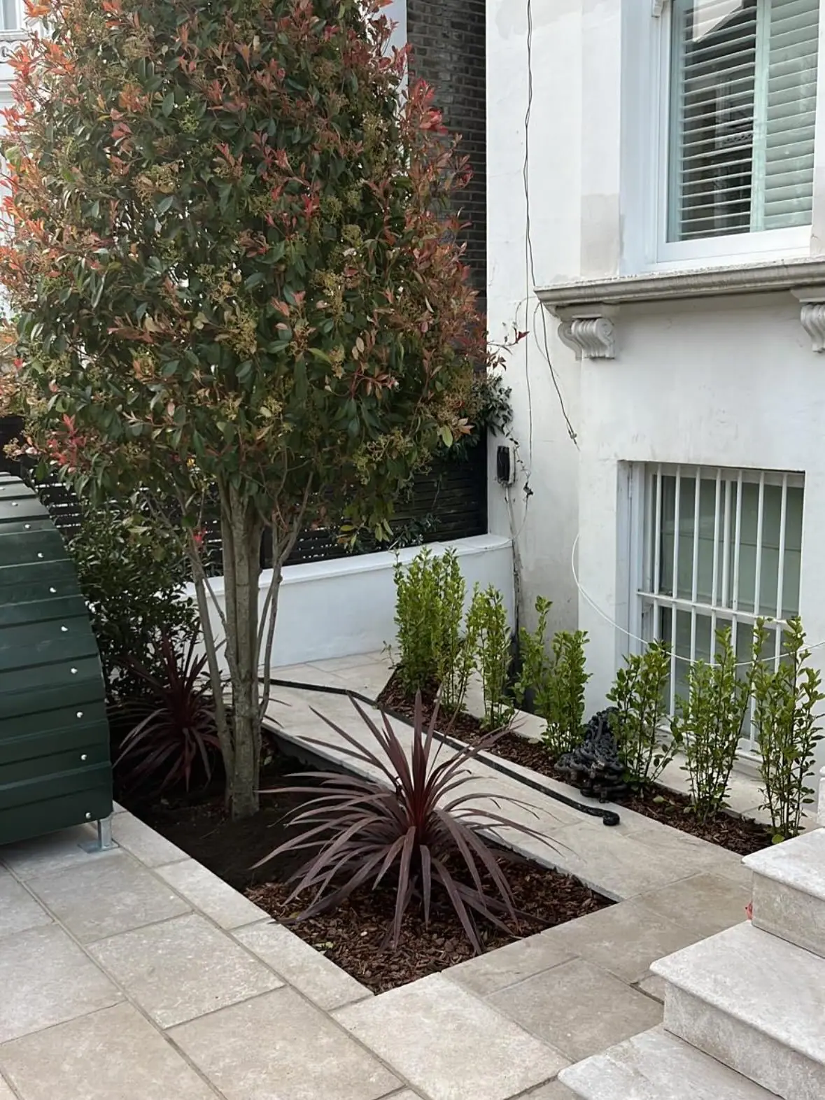 The planting bed with a tree, edged in stone
