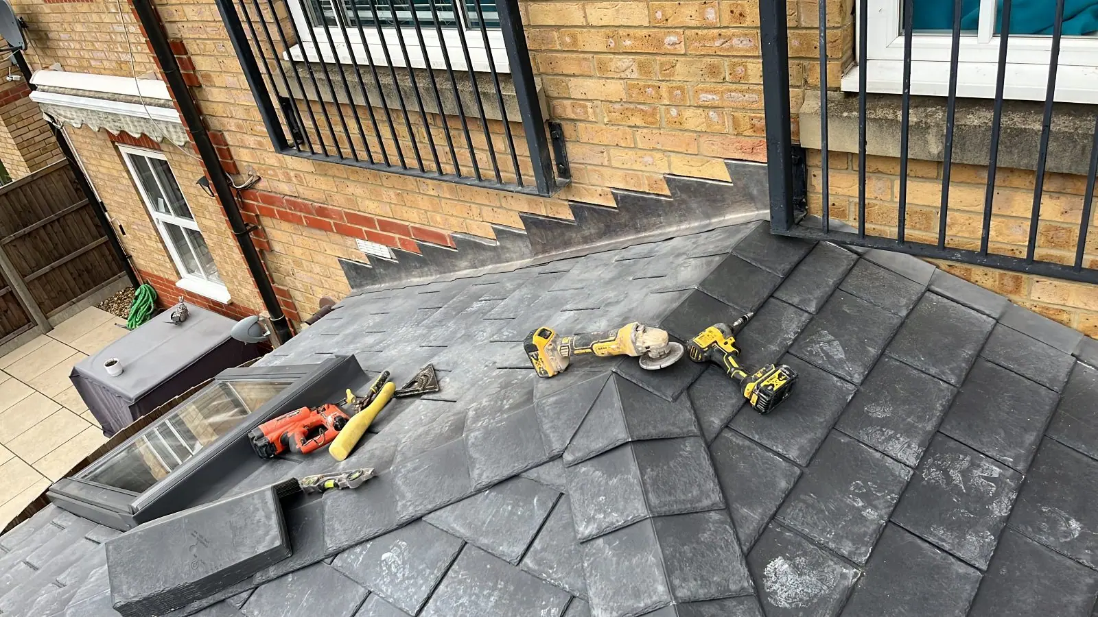 Lead upstand and stepped flashing to the wall of a low-pitch slate roof