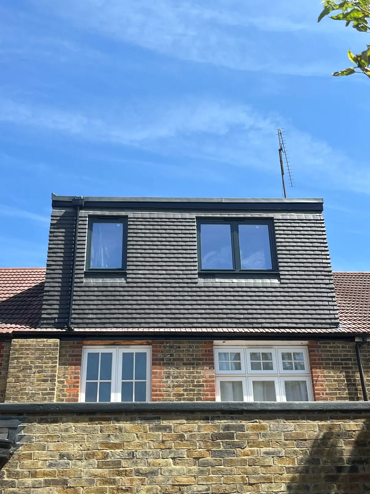 A full-width rear dormer clad in grey tiles