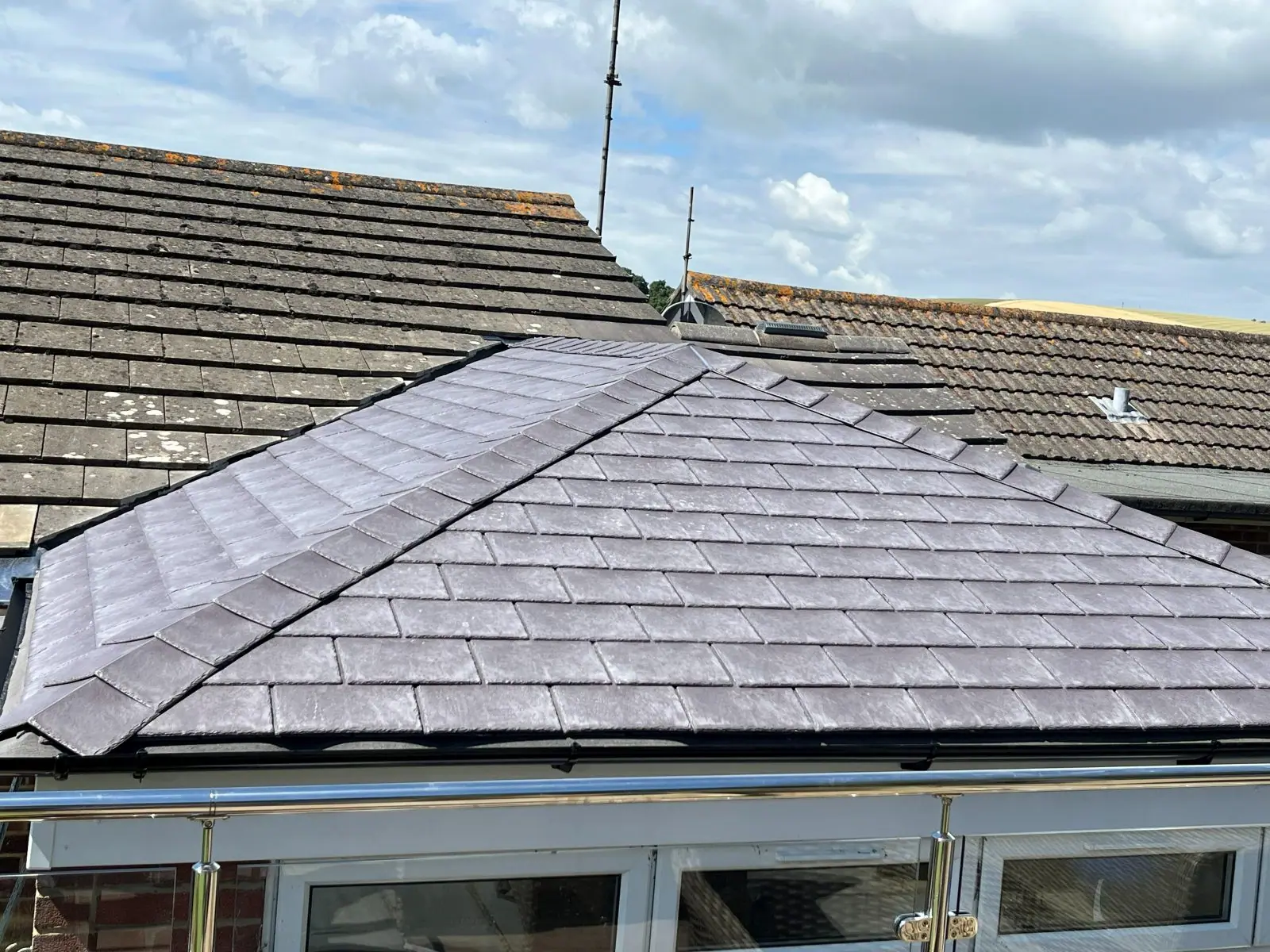 The finished roof seen across the neighbouring roofline, new tiles laid to an even course